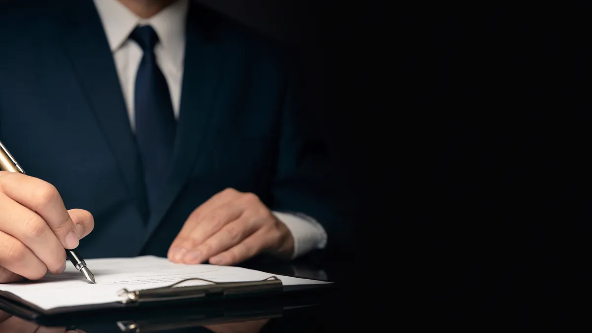 Profissional de terno anotando em caderno sobre mesa